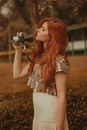 Woman in White and Orange Floral Tank Top Holding Camera