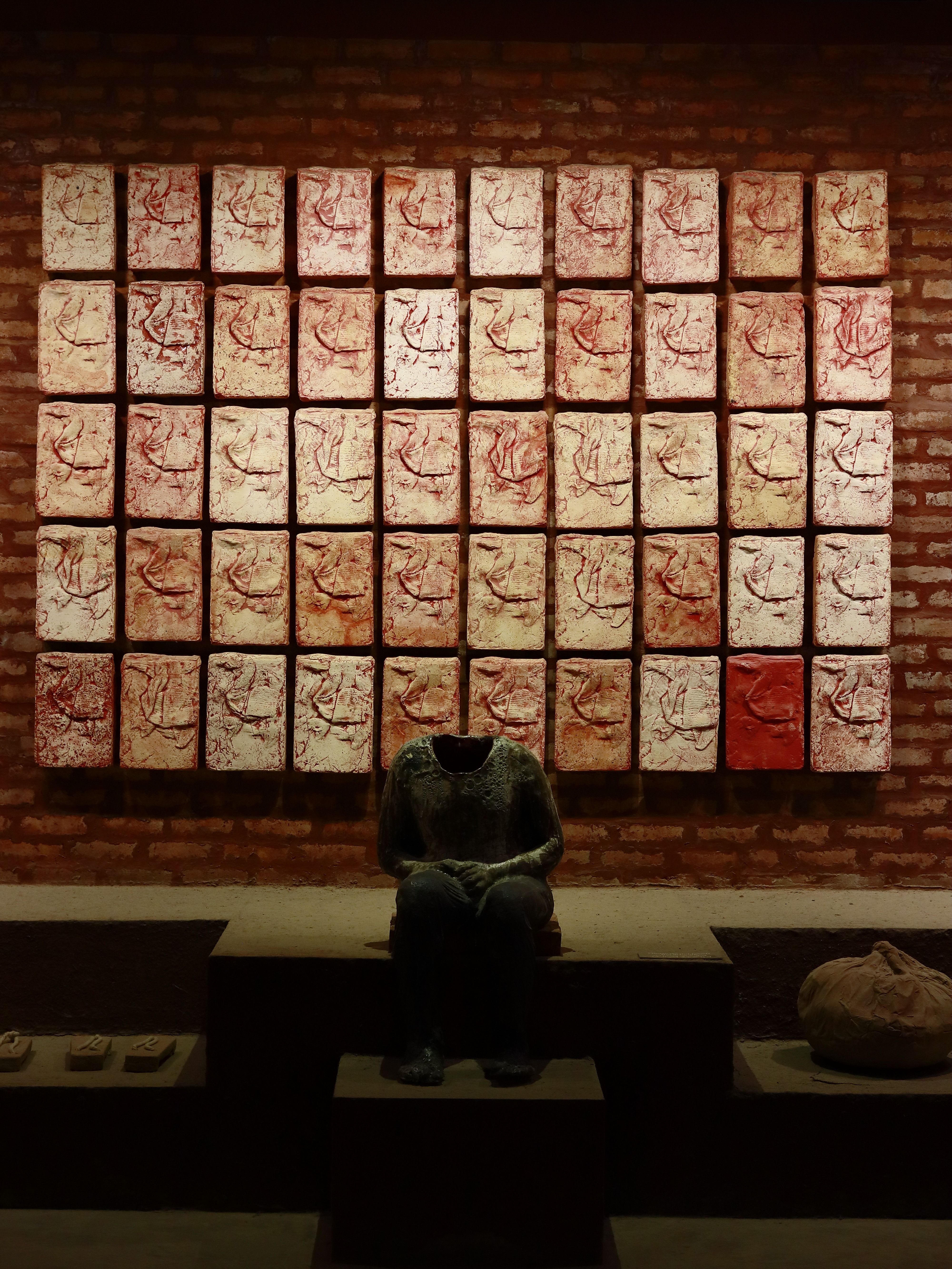 Gratis Installazione artistica con opere murali astratte e una scultura senza testa in una galleria scarsamente illuminata. Foto a disposizione