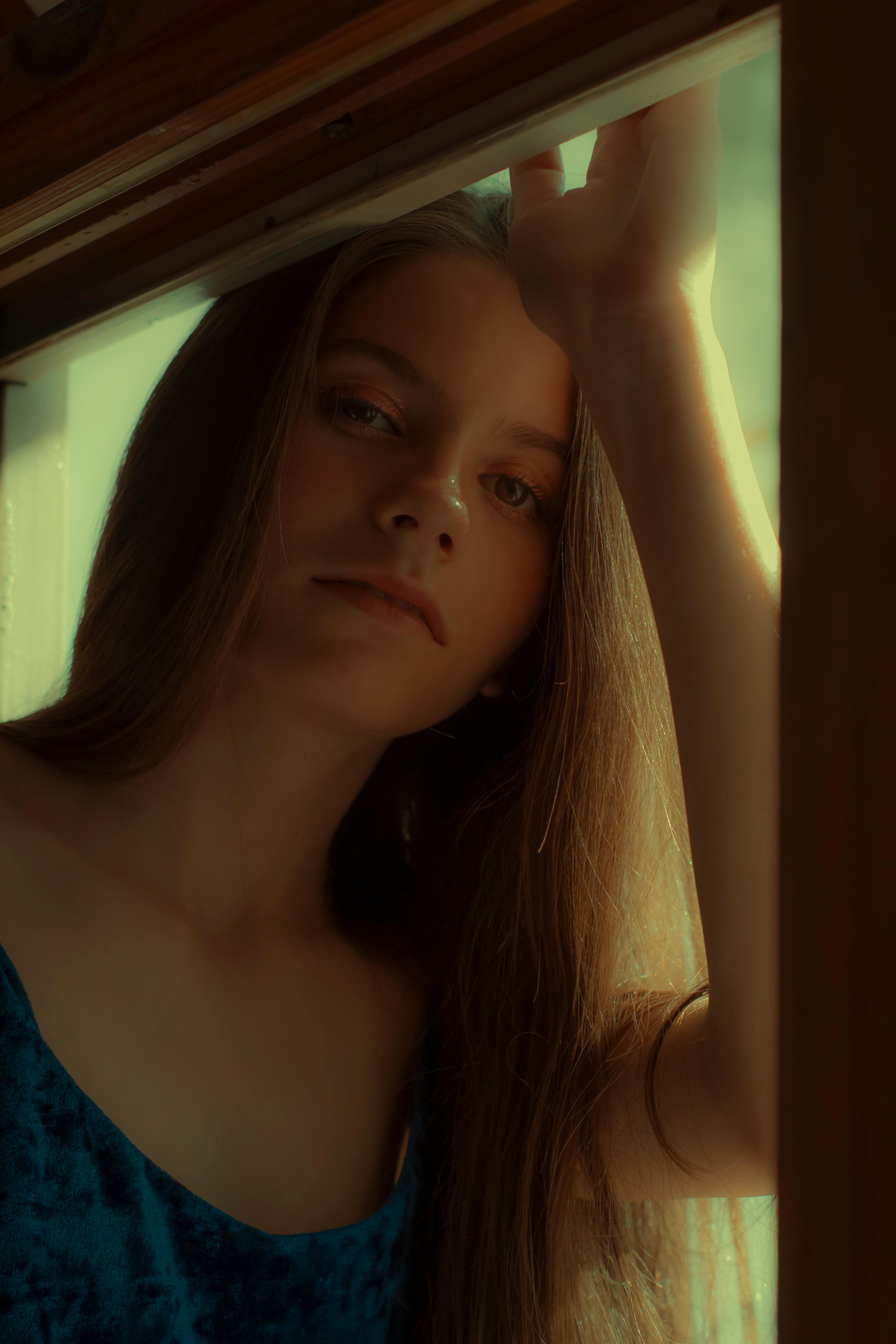 一位体贴的年轻女子沐浴在柔和的自然光线中，透过窗户凝视着