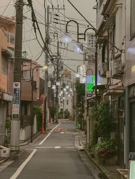 A serene urban street in Tokyo with overhead wires, lanterns, and signs.