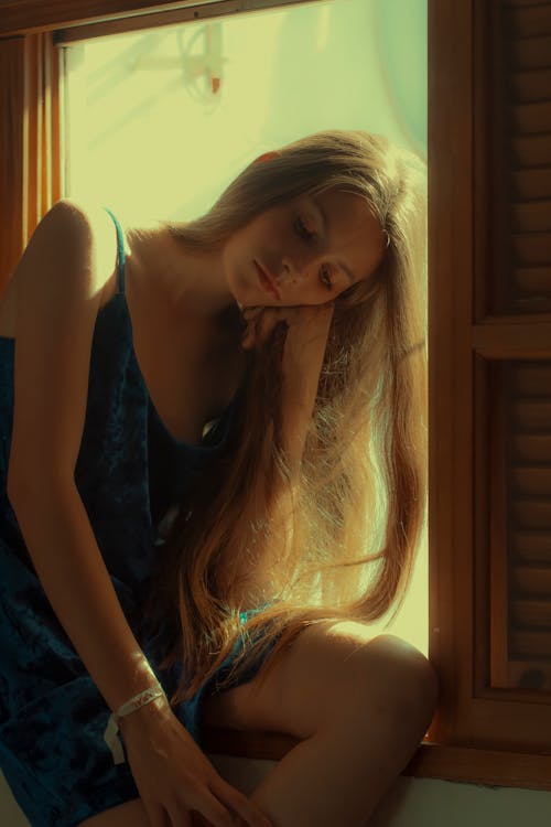 Foto Der Gelangweilten Frau Im Blauen ärmellosen Kleid, Das Auf Fenster Sitzt