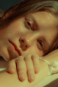 Intimate headshot of a woman resting her head gently, captured in warm tones.