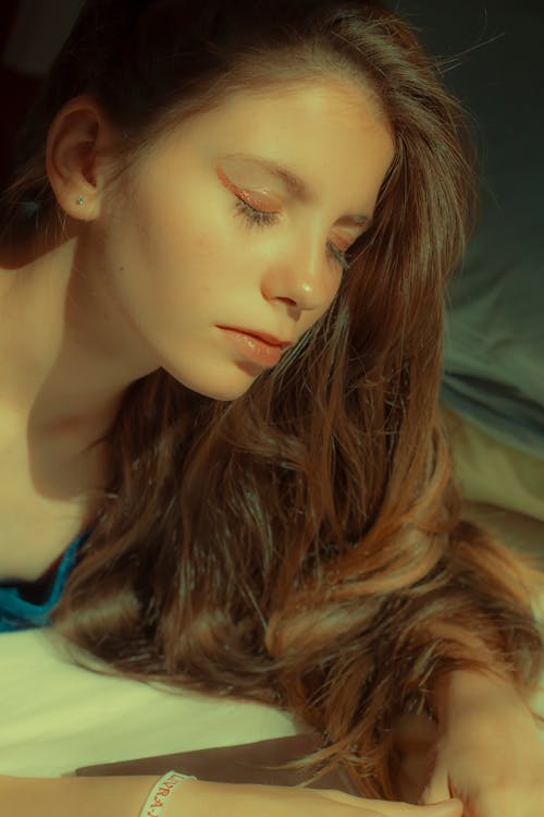 Close-up Photo of Woman in Blue Shirt Lying in Bed With Her Eyes Closed