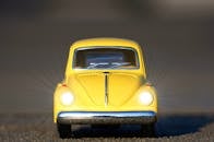 一辆黄色玩具车开着前灯的特写，凸显了经典的复古设计