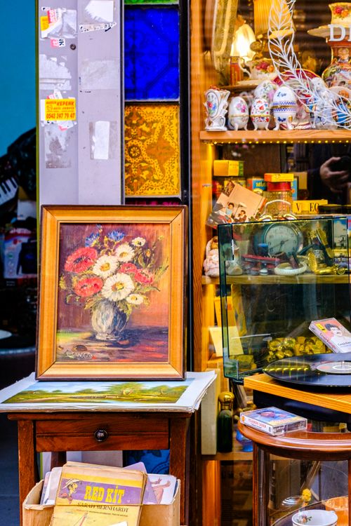 Free Colorful flea market booth featuring a framed floral painting and vintage collectibles. Stock Photo