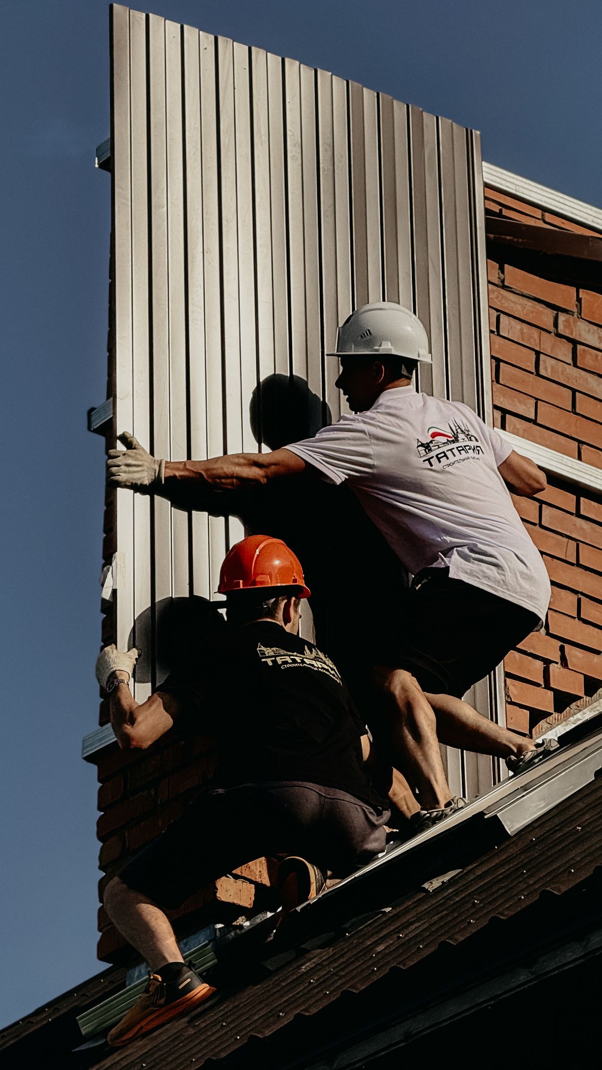 Handwerker montieren Metall-Dachkonstruktion an einem Wohnhaus, Arbeit in vollem Gange