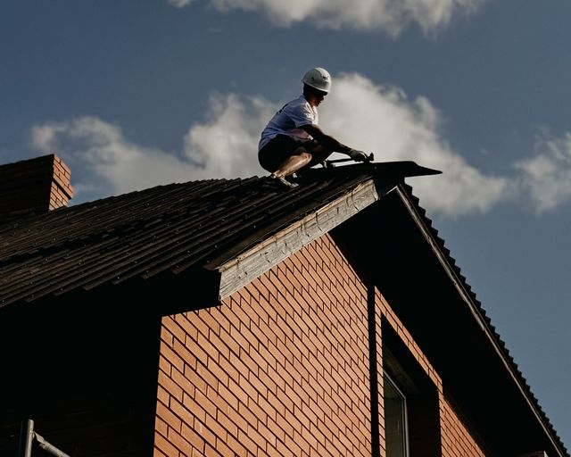 Roof repair in sunshine Roofer in protective gear repairing a roof on a sunny day