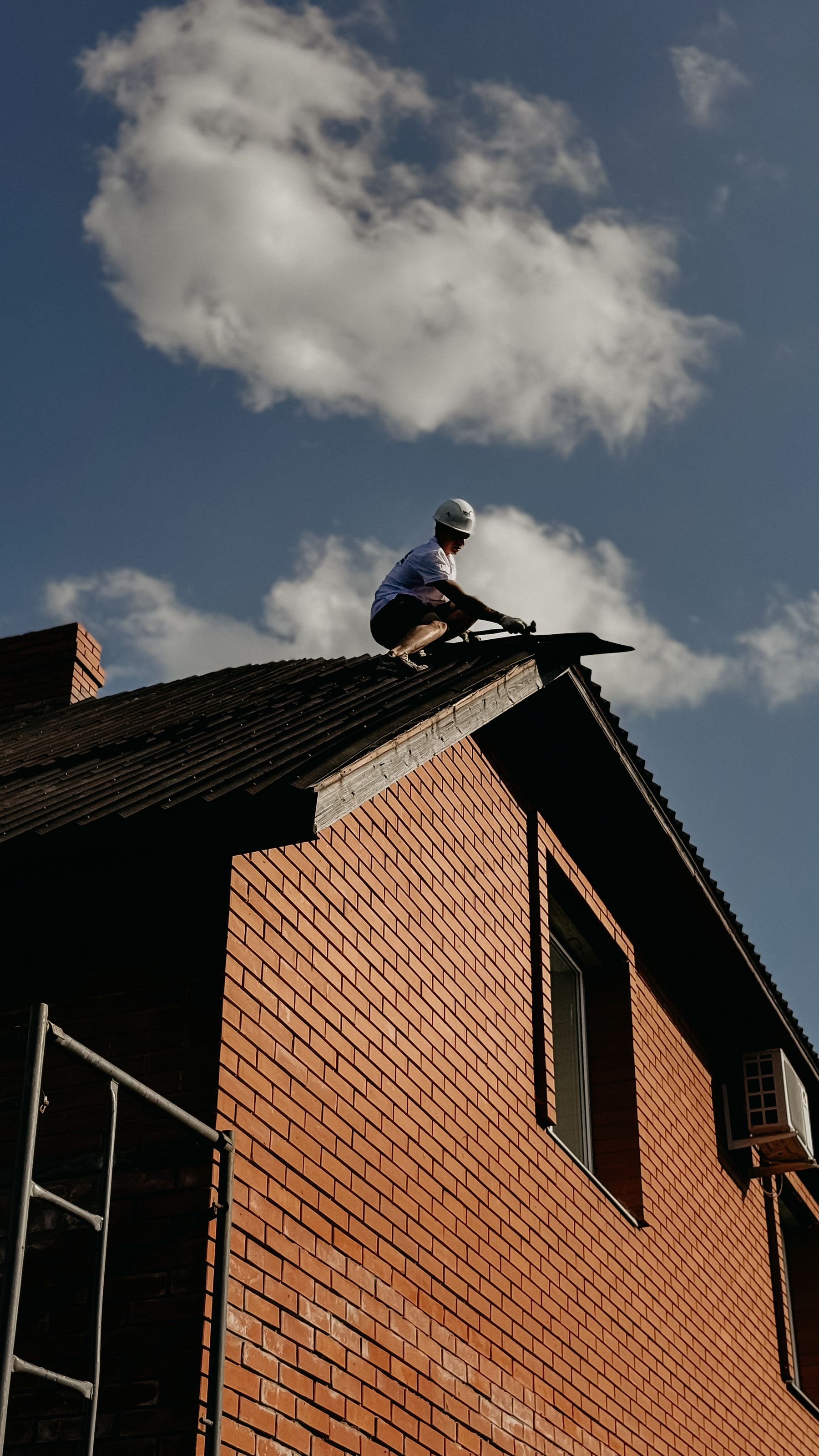 Contractor repairing roof on brick house