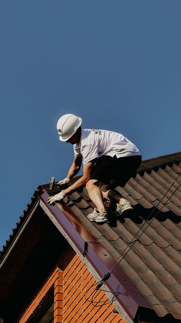 Professional roofer in safety gear repairing a residential roof