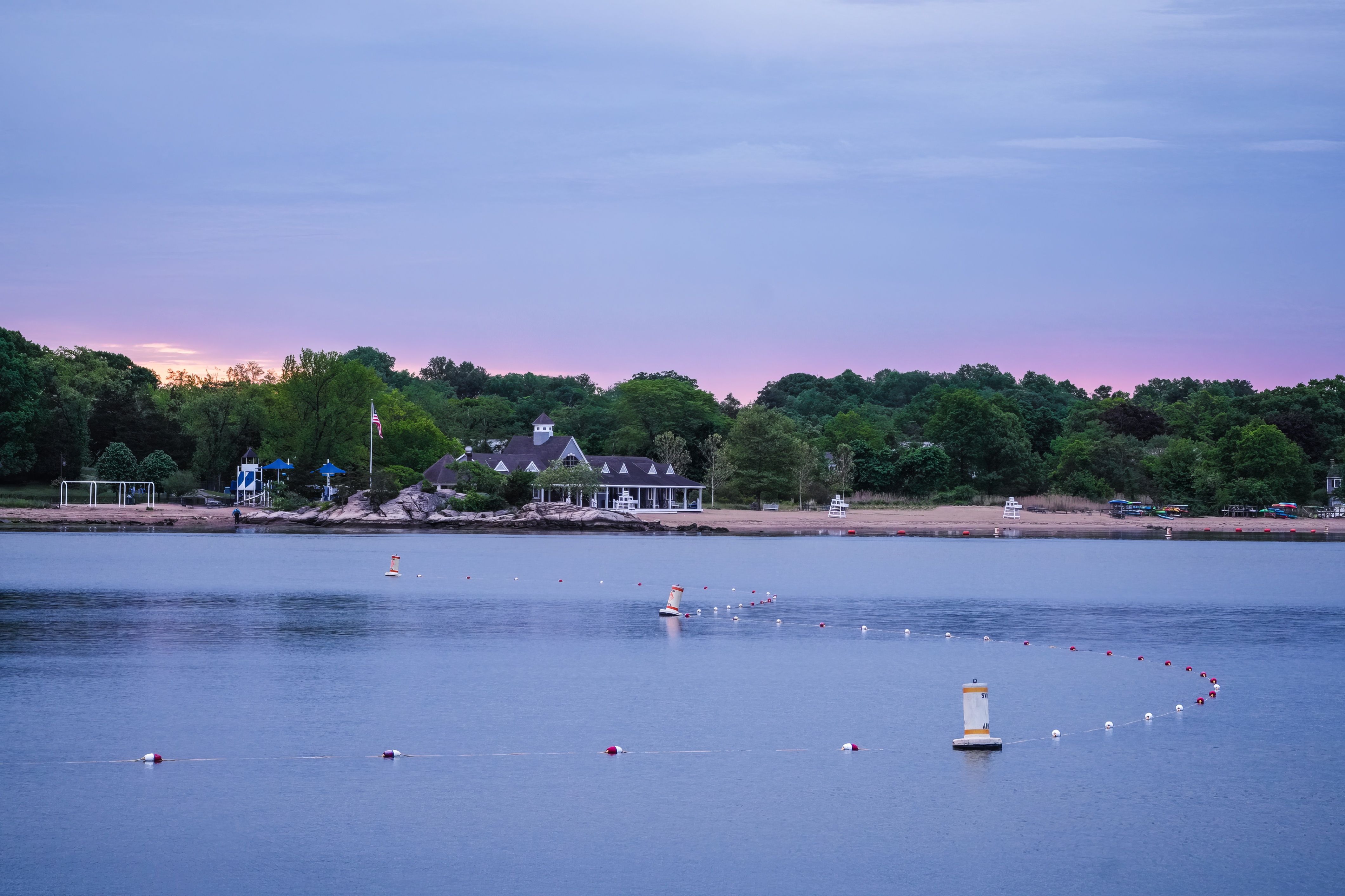 Tranquil lakeside scene at dusk with a serene pink sky in the background.