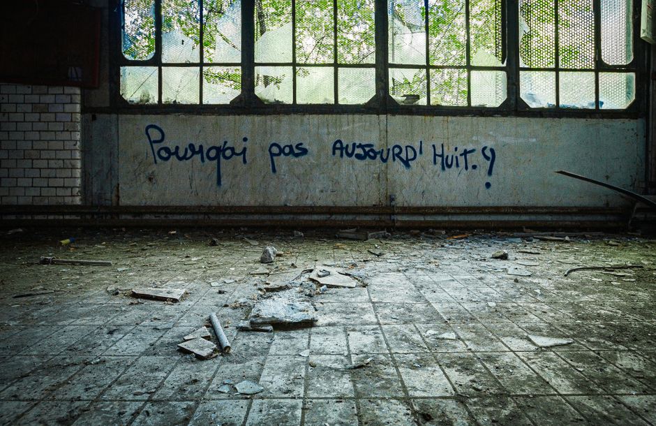Eerie view of a neglected industrial interior covered in graffiti.