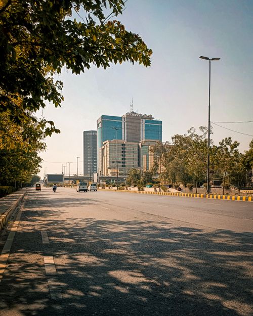 Free A sunny day view of a city street lined with trees and modern office buildings. Stock Photo