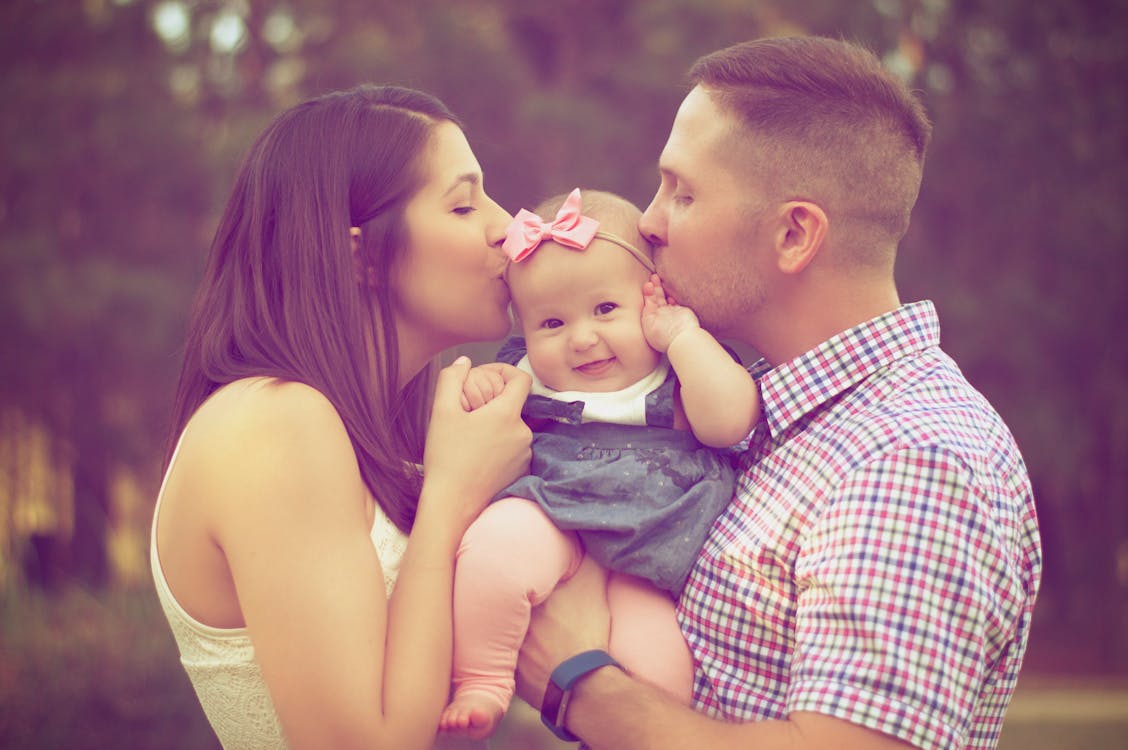 Couple Kissing Baby While Carry