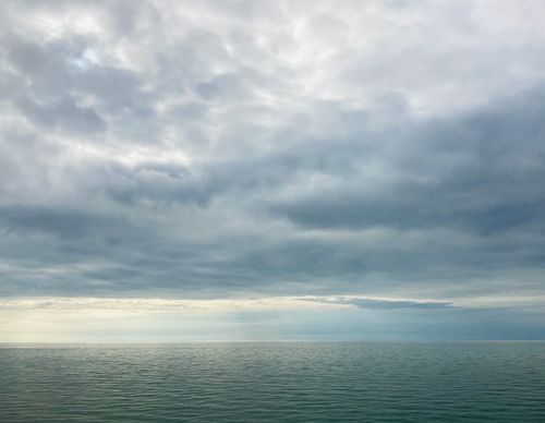 Free Calm ocean waters meeting a cloudy sky, creating a soothing seascape. Stock Photo