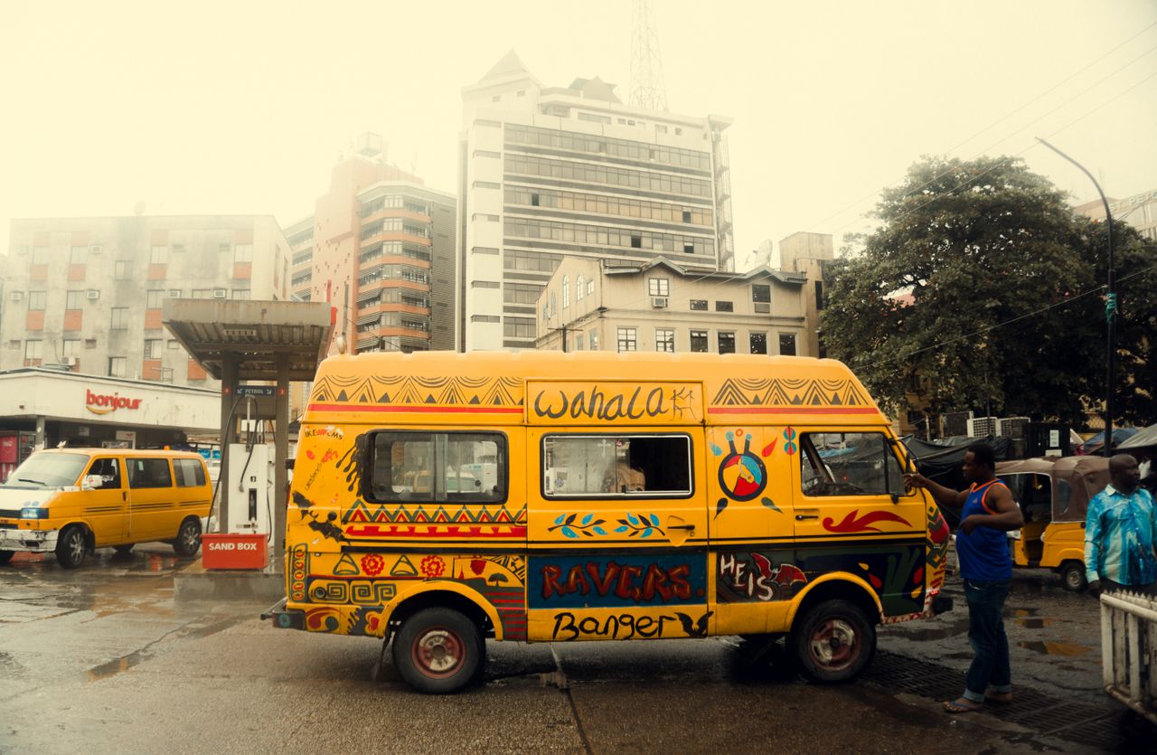 vibrant yellow van parked on a rainy city street with urban backdrop