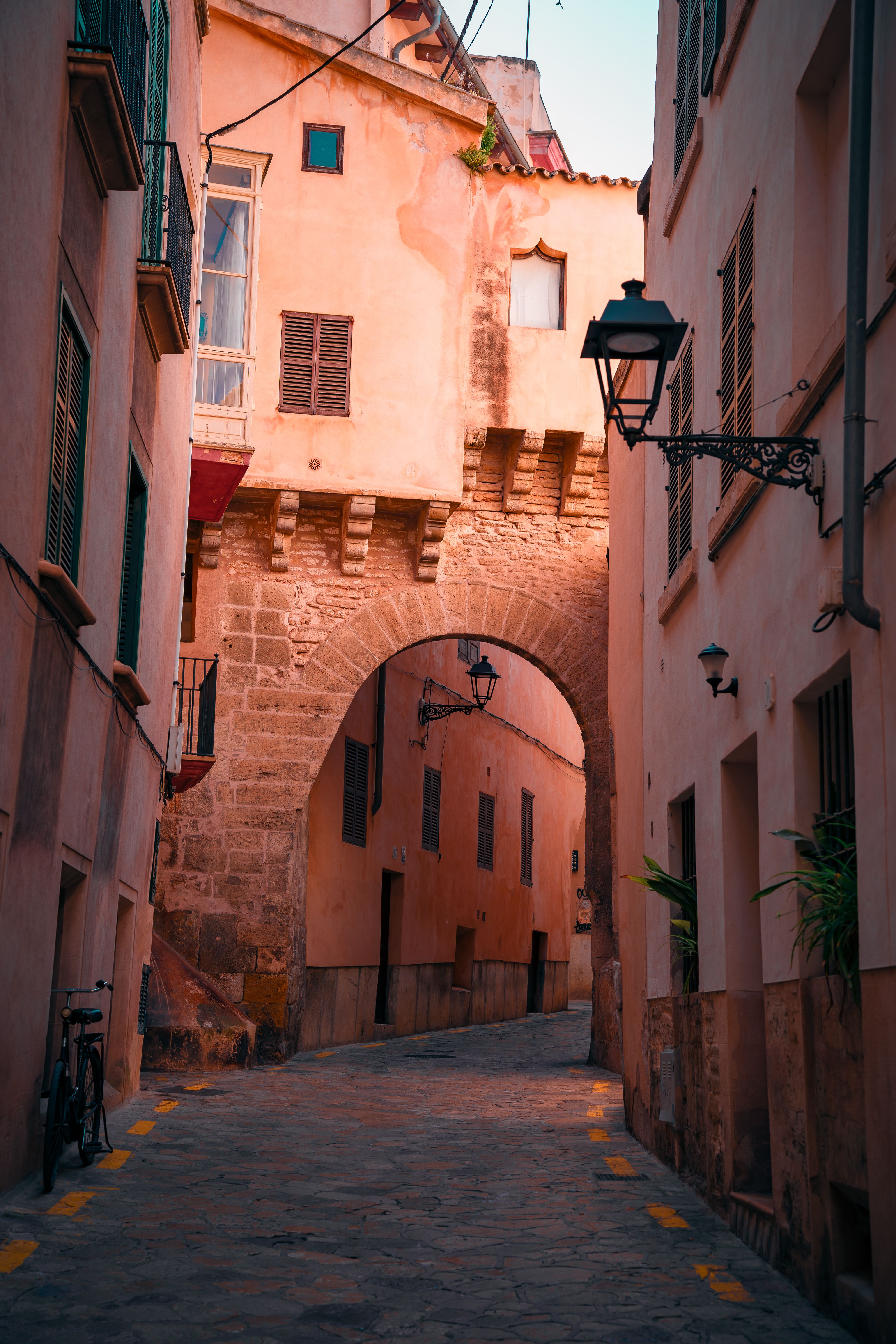 Explore the enchanting narrow streets of Palma de Mallorca, featuring historic architecture bathed in warm sunset light.