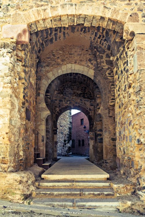 Free Explore a stunning stone archway leading to a medieval building, showcasing intricate old-world architecture. Stock Photo