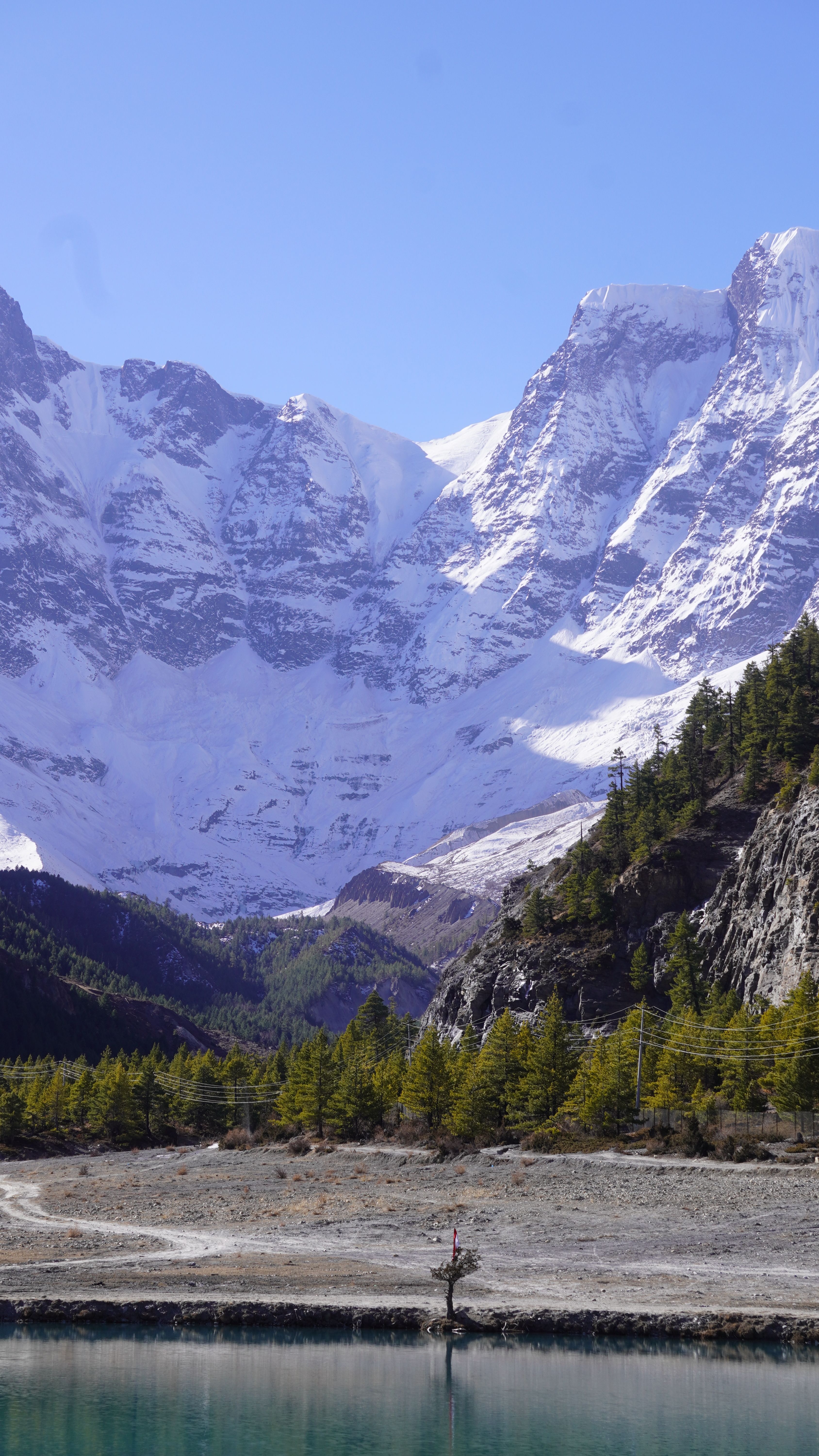 Turquoise glacial lake below snow peaks in Manang