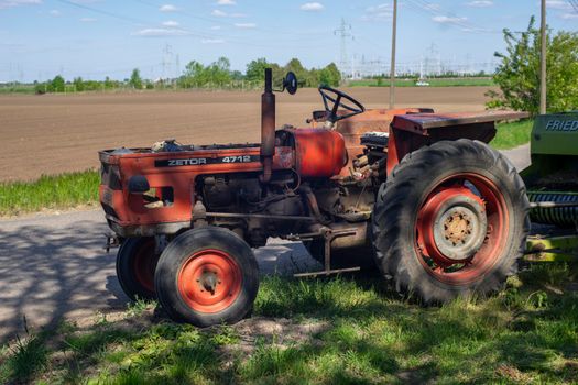 A classic Zetor 4712 tractor parked near an open field under a clear blue sky.