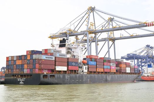 Cargo vessel moored at Kochi, Kerala, India, showcasing global container shipping with cranes in background.