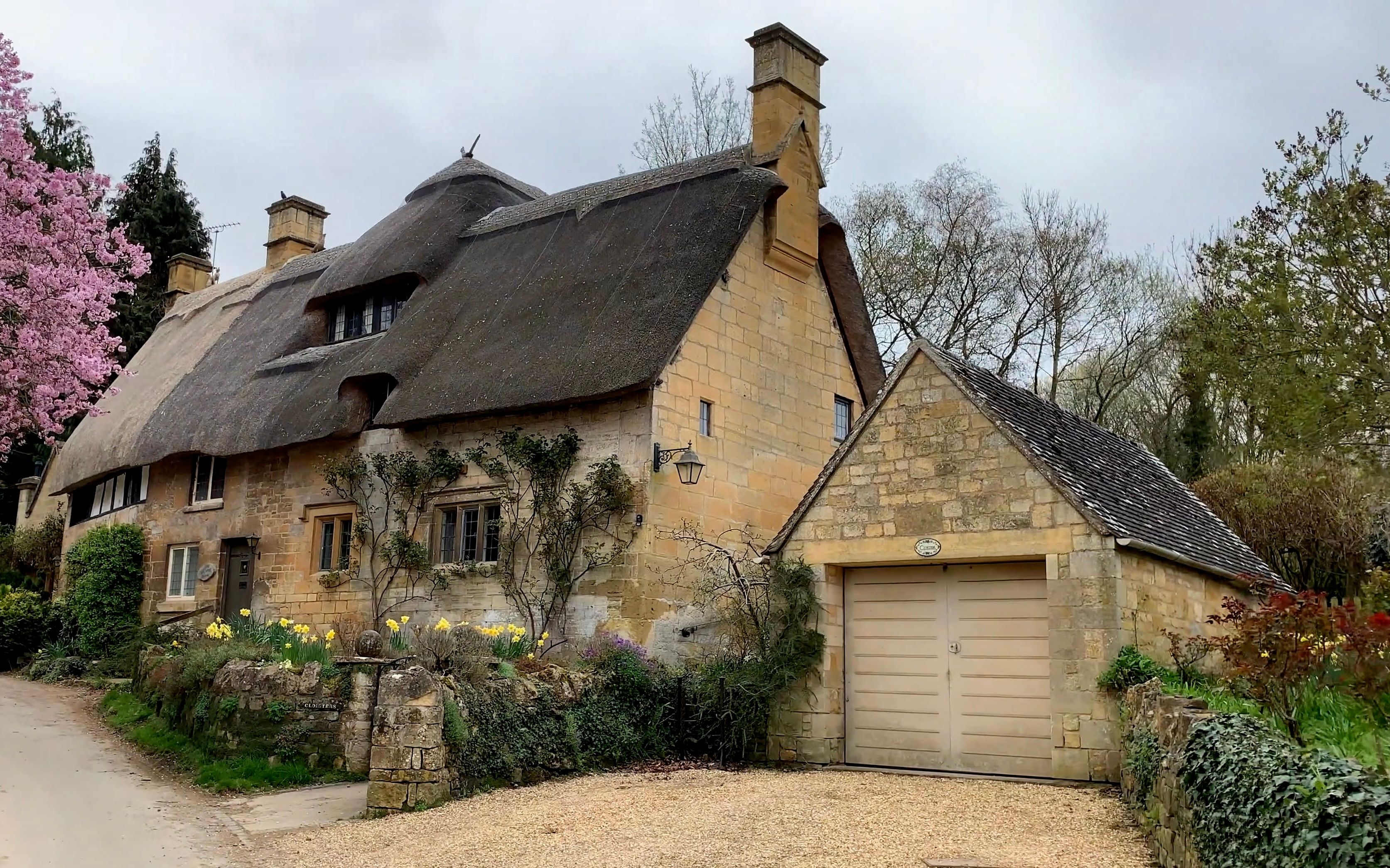 Quaint thatched cottage in Stanton, Cotswolds with unique architecture and spring blooms.
