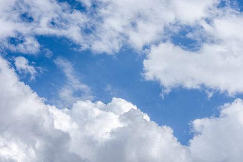 Free A serene photo of a bright blue sky with scattered fluffy white clouds, perfect for a tranquil backdrop. Stock Photo