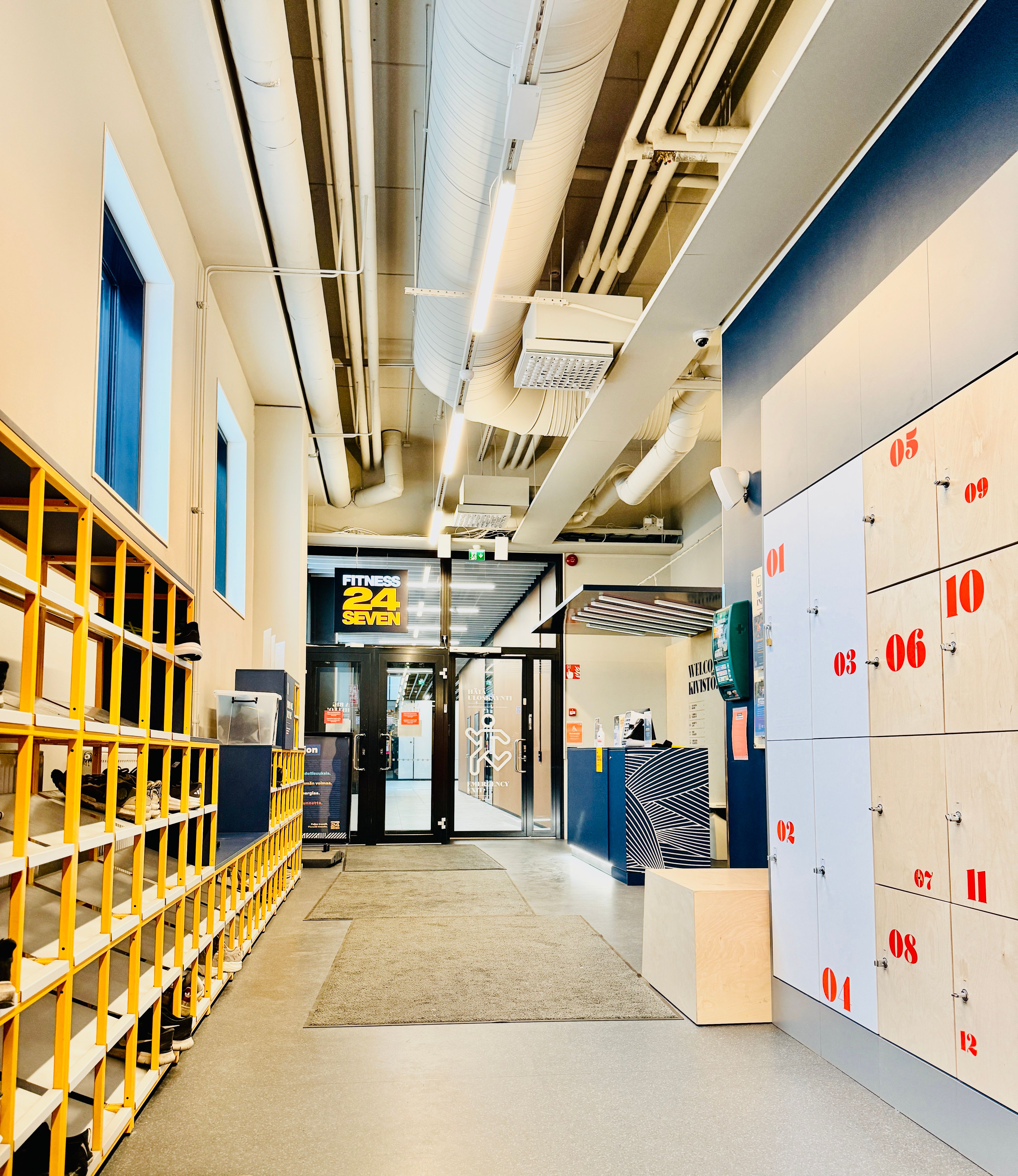 Bright and organized modern gym entrance with lockers, reception desk, and clean layout.