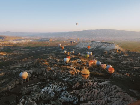 Stunning aerial shot of hot air balloons over Cappadocia's unique landscape at sunrise.