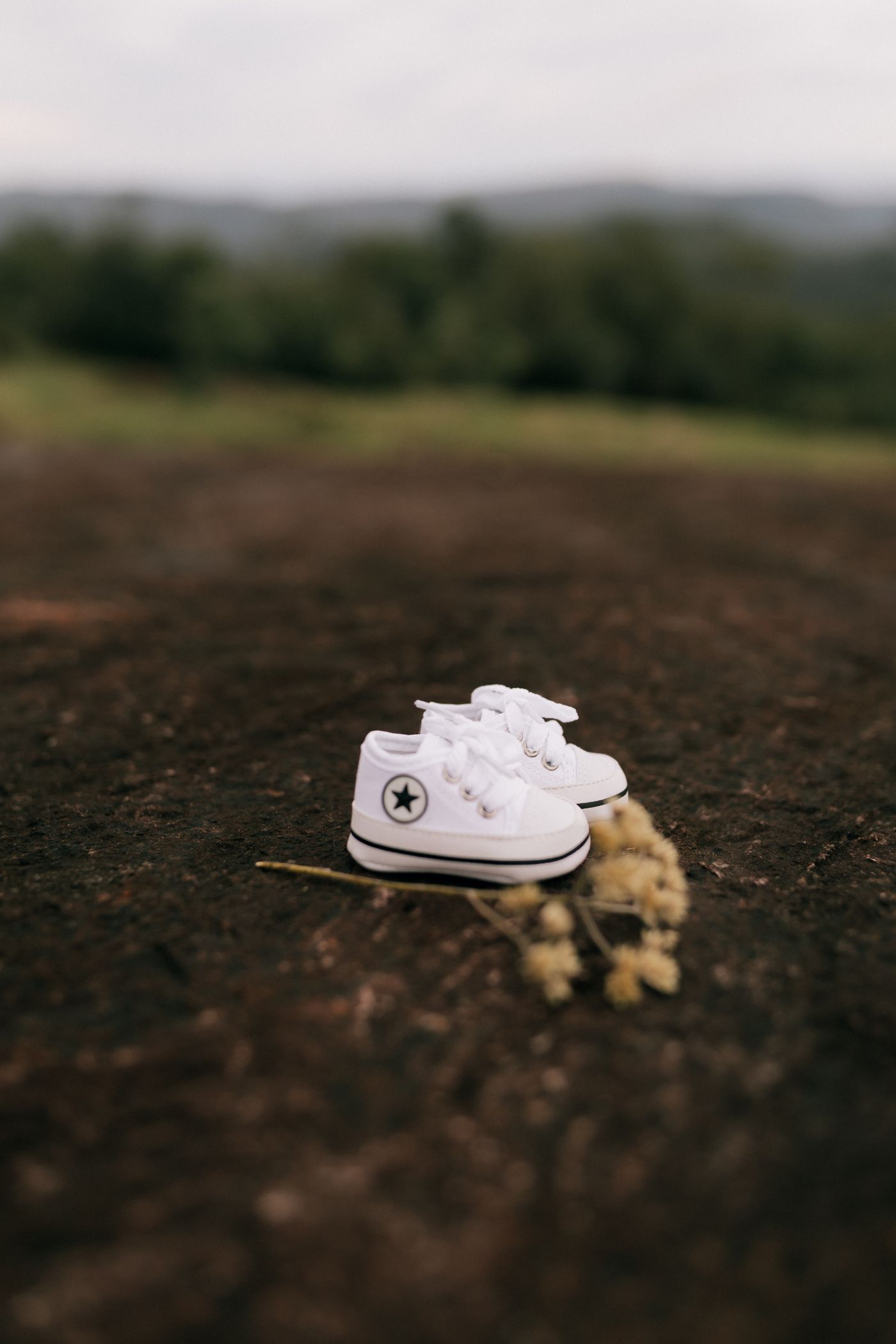 White toddler sneakers placed outdoors on soft earth