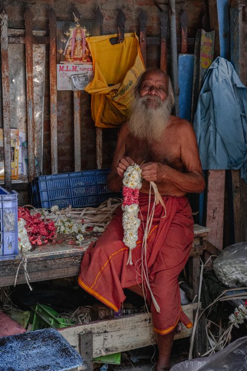Free An elderly man creating intricate flower garlands in a local shop in Тируччираппалли, India. Stock Photo