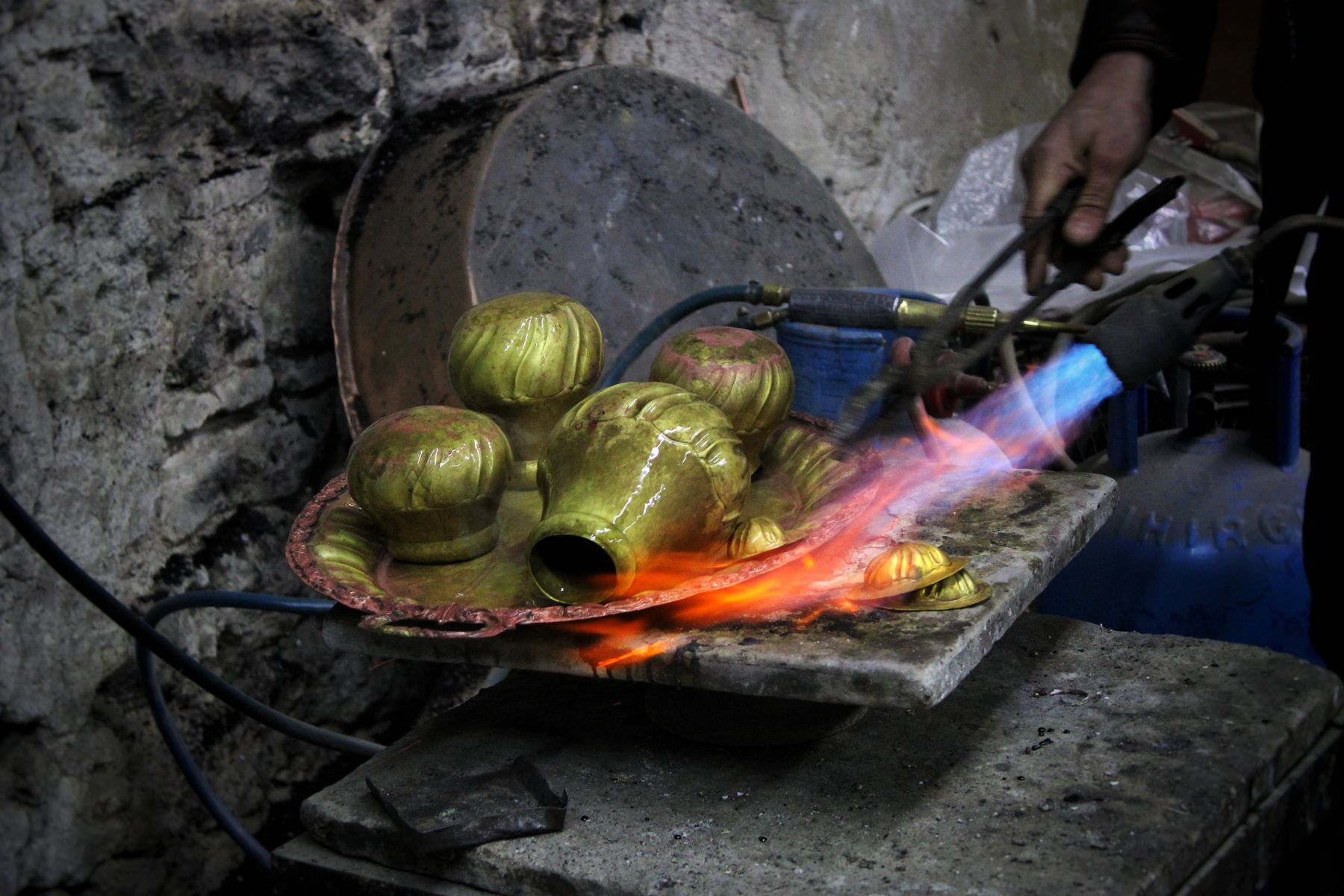 Craftsman heating ornate metalwork with a blowtorch