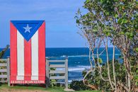 Colorful Puerto Rican flag mural at La Lomita de los Vientos with ocean view.