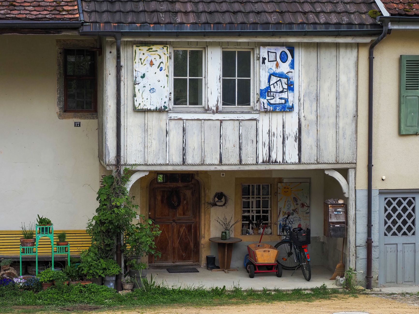 Rustic house exterior showcasing artistic shutters and cozy vintage decor, ideal for creative inspiration.