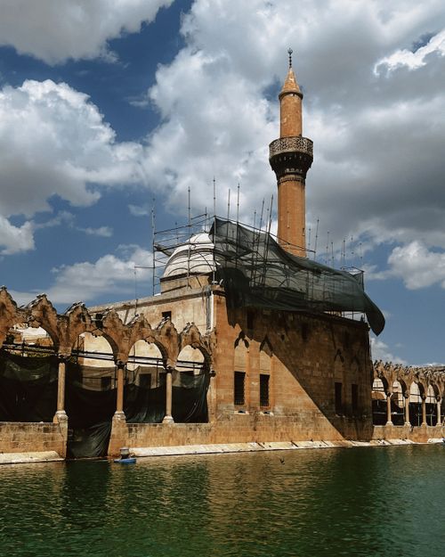Free The Halil-ur Rahman Mosque with its minaret reflecting in tranquil waters, under a bright sky. Stock Photo