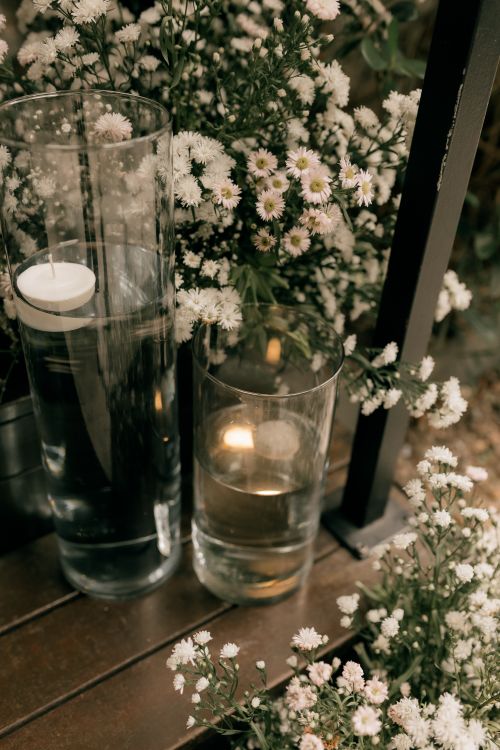 Free A serene outdoor setting with white flowers and candles in clear vases, creating a calm ambiance. Stock Photo