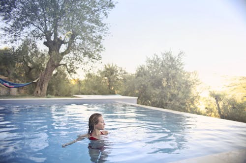 Photo of Woman in Red Bikini Standing Inside Swimming Pool Looking Away