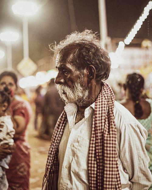 Free Elderly man at a bustling night market, warm lights, candid street portrait. Stock Photo