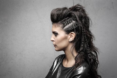 Free Portrait of a fashionable woman with an edgy hairstyle and black attire on a textured background. Stock Photo