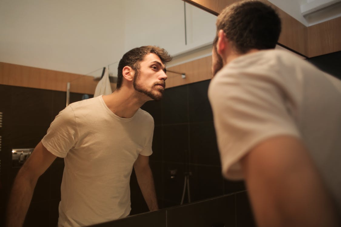 Free Stylish concentrated man looking in mirror in bathroom Stock Photo