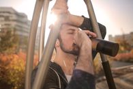 健美男子在城市的阳光下进行户外锻炼，中途休息补水