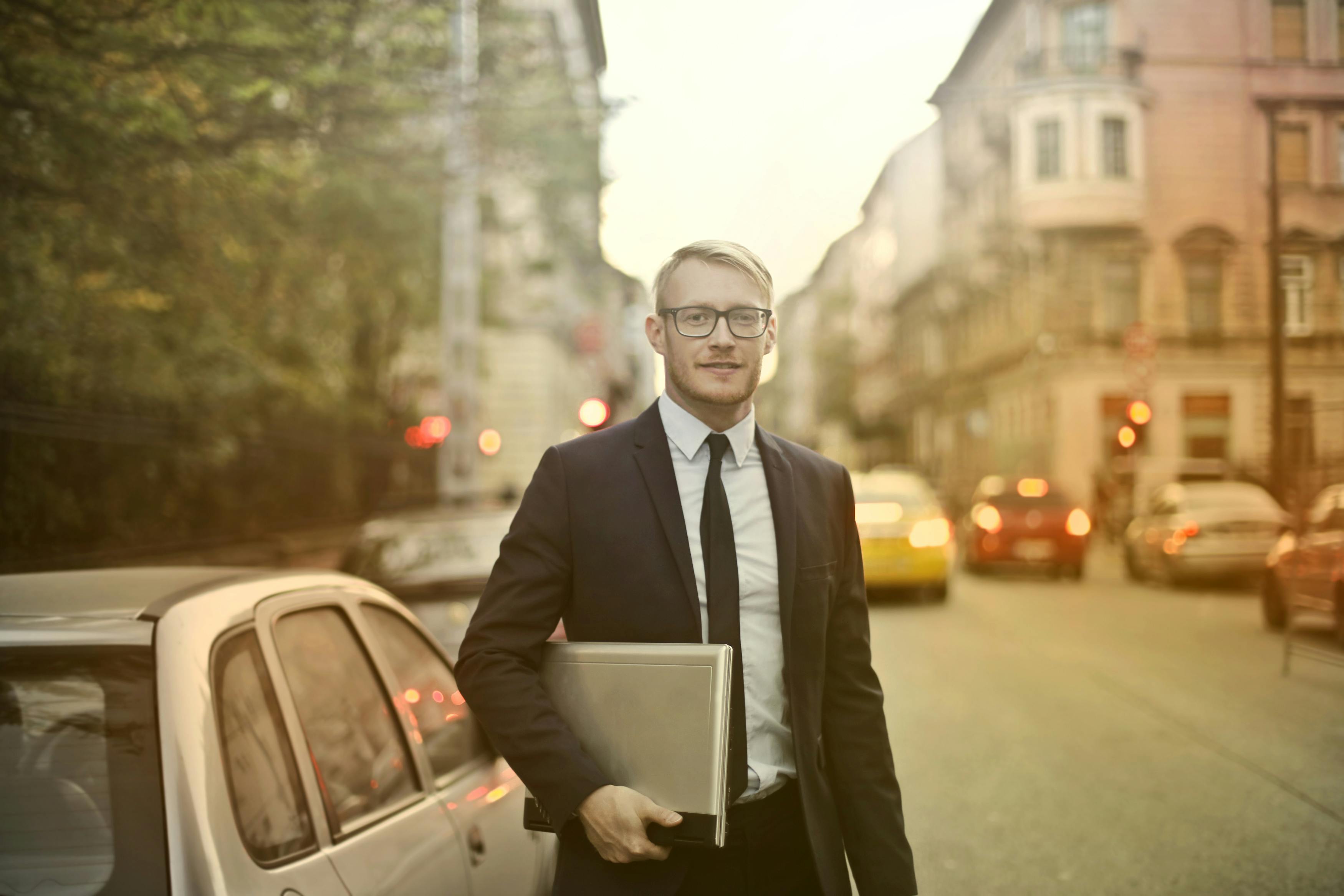 determined smiling businessman with laptop on street