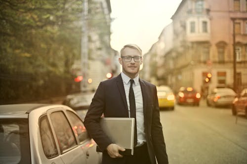 Determined smiling businessman with laptop on street
