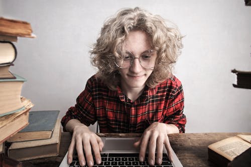 Free Content young male student using laptop in library Stock Photo