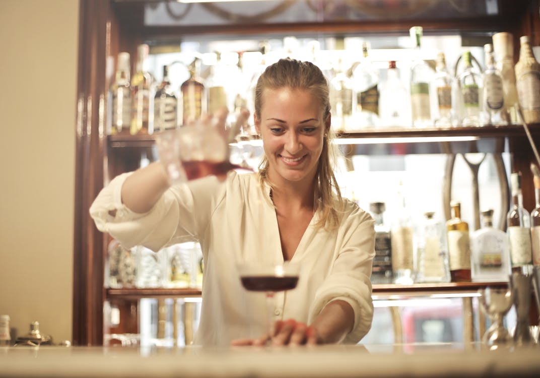 Free Cheerful female bartender pouring cocktail in bar Stock Photo
