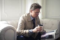 一位专业人士在现代化的休息室里，一边喝咖啡一边看杂志