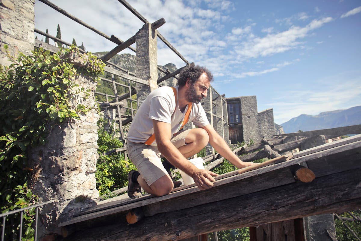 Focused man building roof of wooden construction
