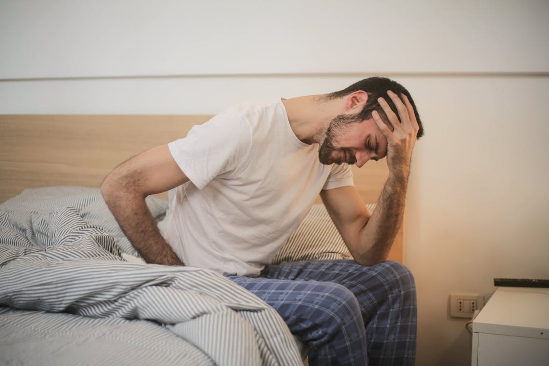 무료 아침에 두통으로 고통받는 잠옷에 젊은 남자 스톡 사진