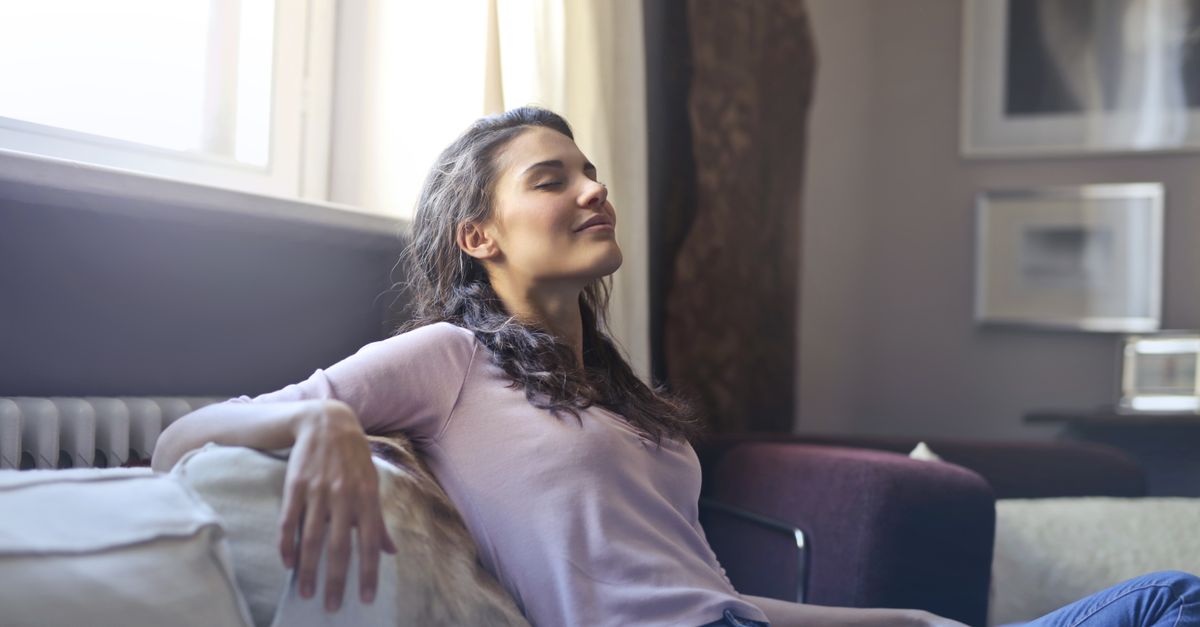 person sitting on a couch with eyes closed, natural light, calm atmosphere