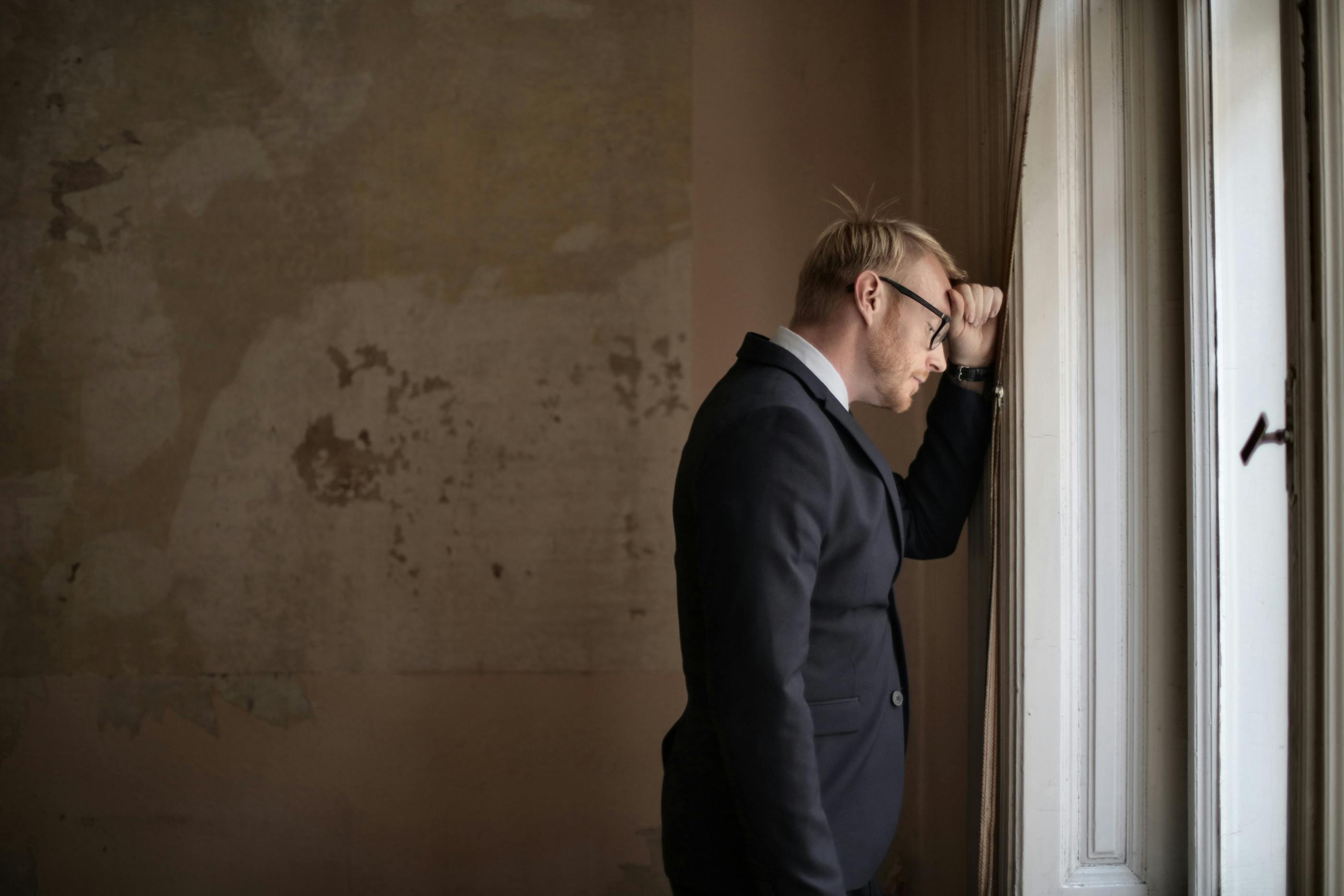 desperate evicted male entrepreneur standing near window