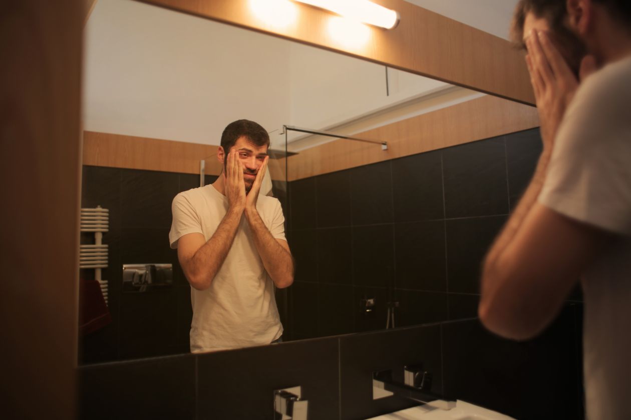 Man examining his hair in bathroom mirror